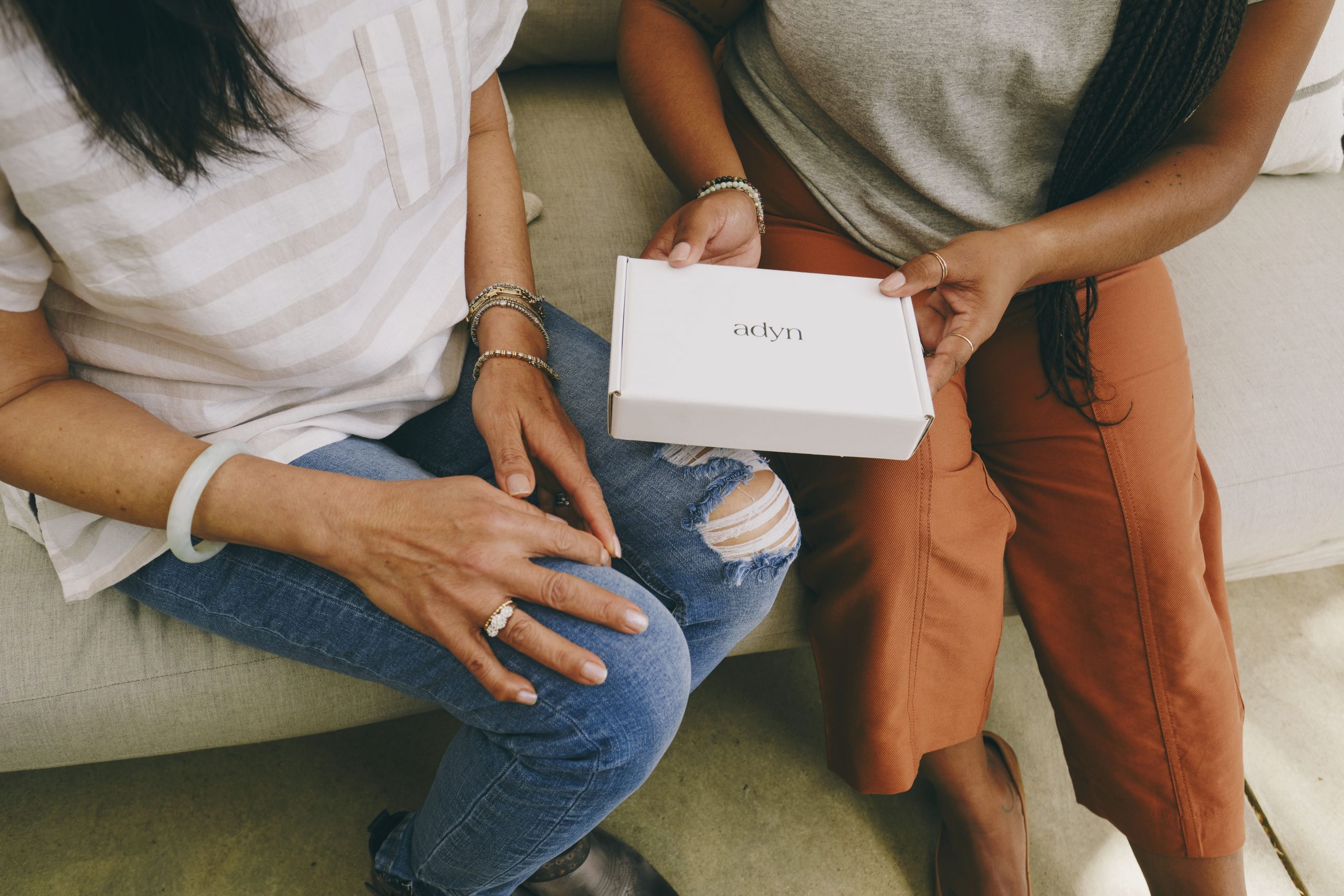 overhead shot of two people on a couch, one holding an adyn box
