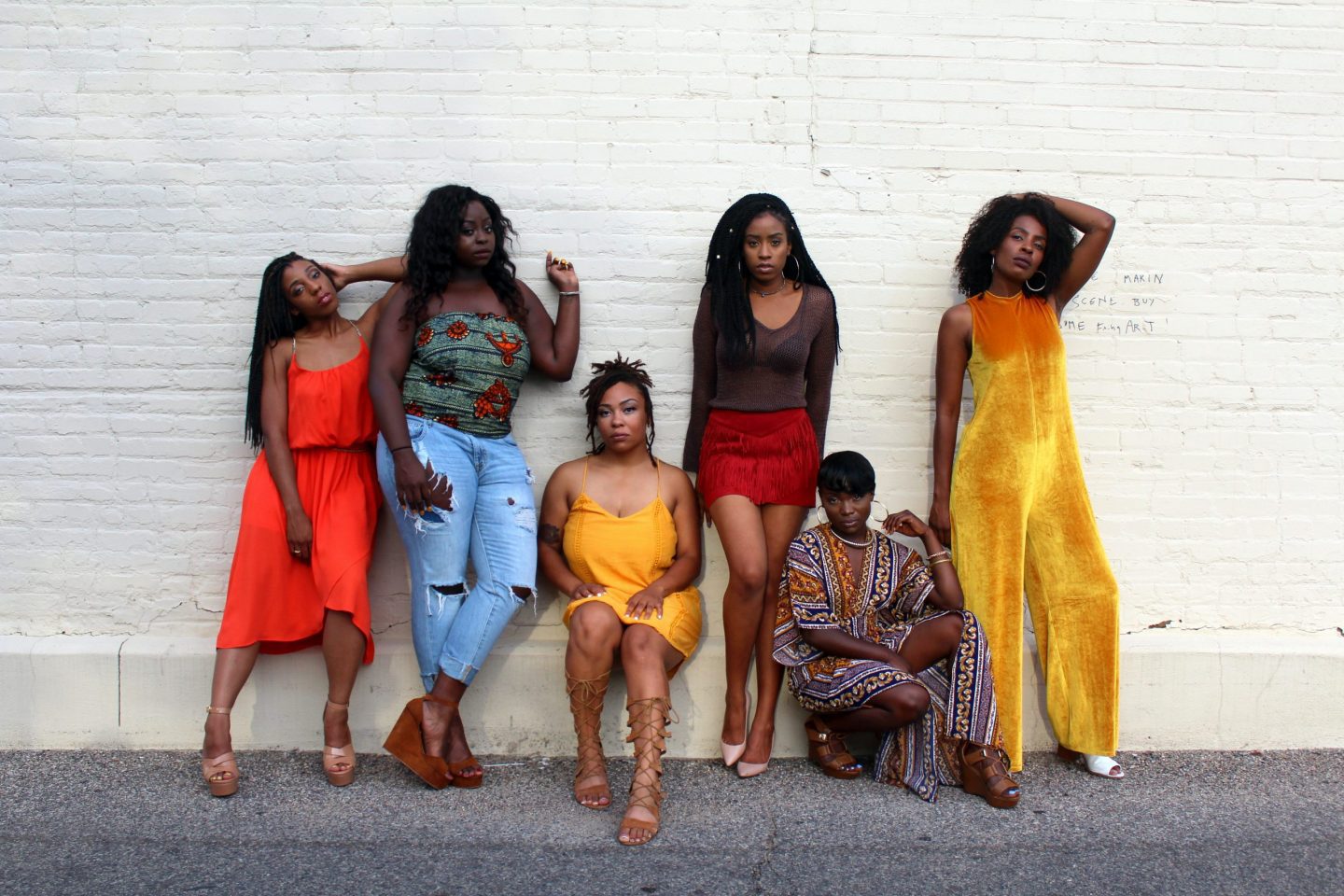 Confident and stylish women posing together in front of a wall.
