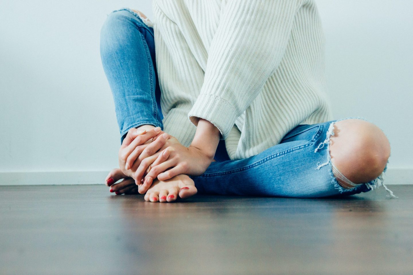 Image of woman in jeans and a white shirt sitting on the ground
